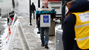 Election worker carrying ballots outside in snow