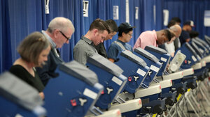 Line of voters at booths in front of blue curtain