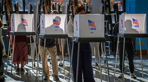 People voting at individual booths with American flags on front