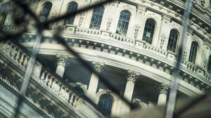 Photo of a government building through links in a fence.