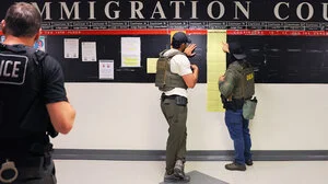 Three immigration enforcement agents in front of a sign that reads "Immigration Court"