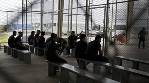 Men detained within a chain link fence